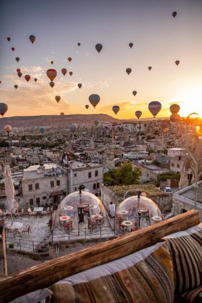Terraza del Charming Cave Hotel en Capadocia con cúpulas transparentes y globos aerostáticos al amanecer