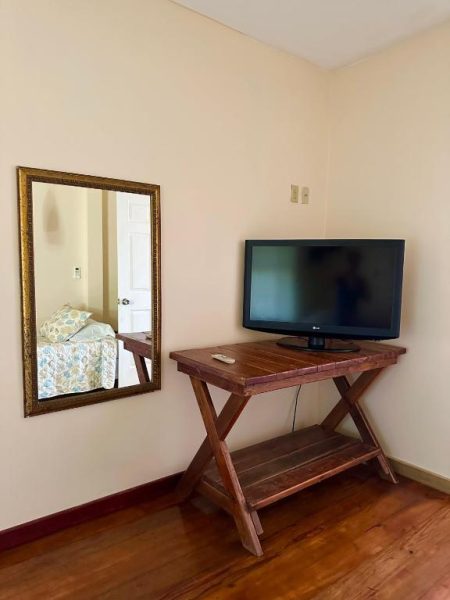 Habitación del hotel Lands End con televisor LG sobre mesa de madera y espejo decorativo dorado