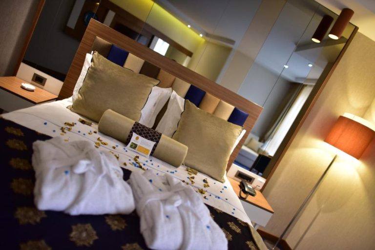 Habitación doble decorada con pétalos y toallas en el Giritligil Hotel, cama con cojines dorados