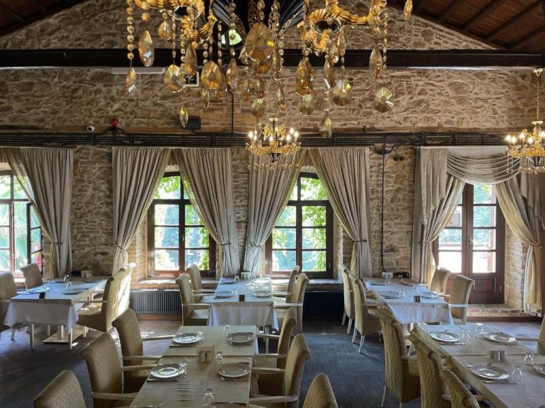 Elegante restaurante del Giritligil Hotel con paredes de piedra, lámparas de cristal y mesas preparadas