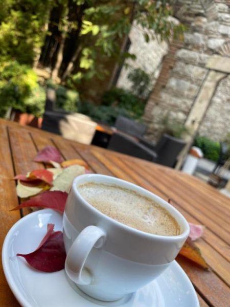Taza de cappuccino en terraza exterior del Giritligil Hotel rodeada de hojas otoñales sobre mesa de madera