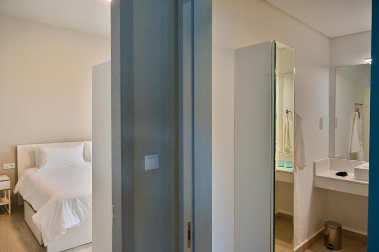 Habitación suite con baño integrado y espejo en Royal Green Wellness Resort, diseño moderno en blanco