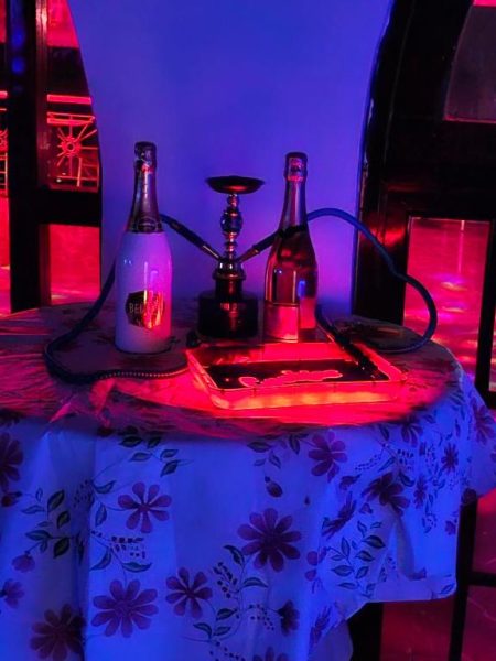 Mesa con hookah y botellas de champán en zona VIP con luces de ambiente del Big Apple Hotel