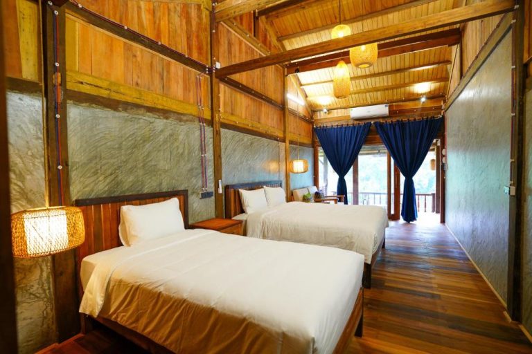 Habitación doble con camas individuales y decoración en madera rústica en Ba Be Jungle Houses