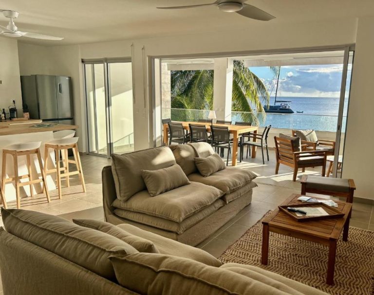 Amplio salón con sofás y terraza con vistas al mar en La Plage Martinique