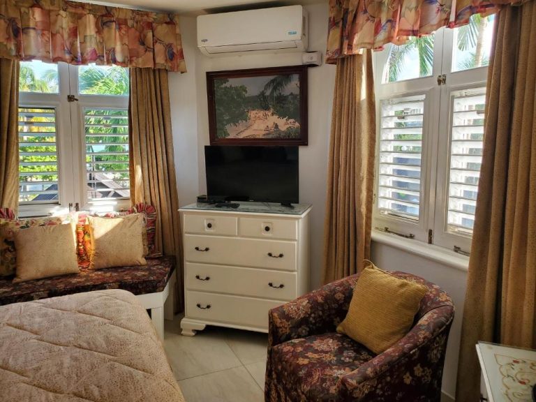 Habitación con TV, cómoda blanca y sillón floral en Sandcastles Resort Ocho Rios Jamaica