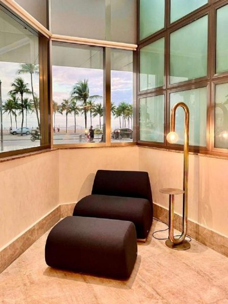 Rincón de lectura con sillón y lámpara dorada con vistas a la playa en Hotel Astoria Palace