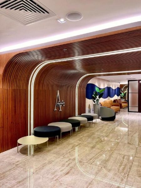 Elegante lobby del Hotel Astoria Palace con paneles de madera curvados, iluminación LED y zona de espera moderna