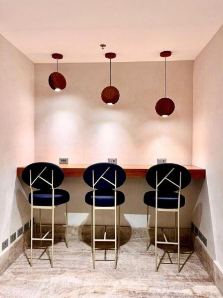 Zona de trabajo con taburetes azules y lámparas colgantes de madera en el Hotel Astoria Palace