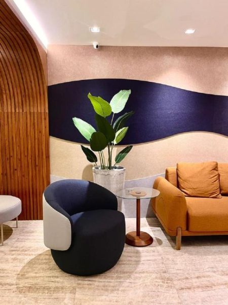 Zona de lobby del Hotel Astoria Palace con sillones modernos, sofá naranja y decoración mural en tonos azules