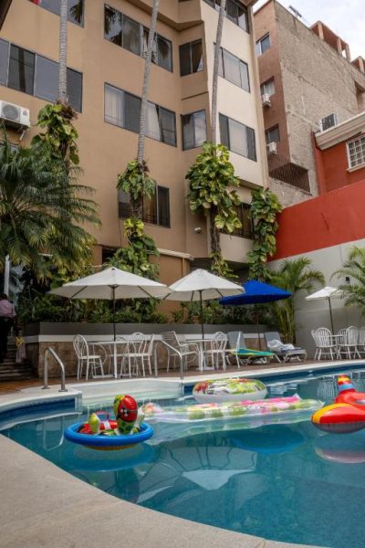 Piscina exterior con flotadores coloridos y zona de descanso del Aparthotel Guijarros