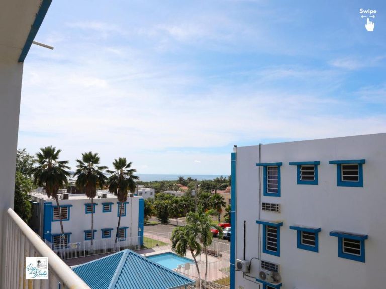 Vista desde balcón de West Coast Apartments con piscina, palmeras y vistas al mar Caribe