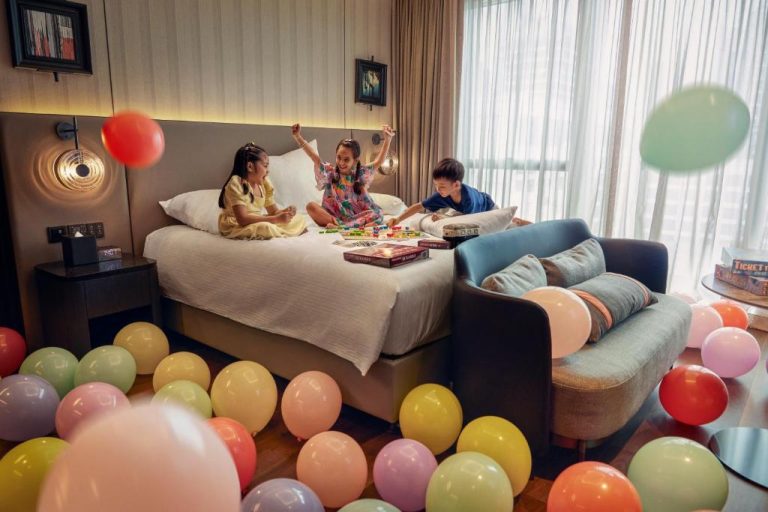 Niños jugando con juegos de mesa en habitación familiar decorada con globos del Pullman Singapore Hill Street