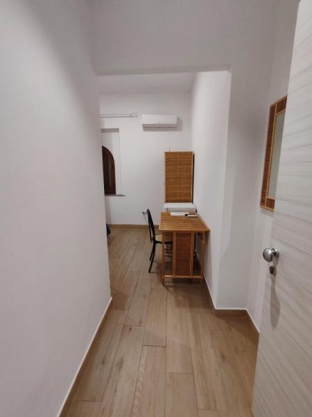 Habitación con escritorio de madera y silla en Hotel Faraglione, suelo laminado y aire acondicionado