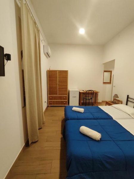 Habitación doble con camas azules y armario de madera en Hotel Faraglione