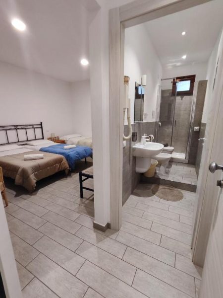 Habitación doble con camas individuales y baño privado con ducha en Hotel Faraglione