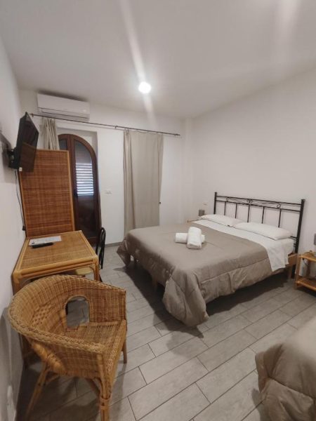 Habitación doble clásica con cama matrimonial y mobiliario de mimbre en Hotel Faraglione