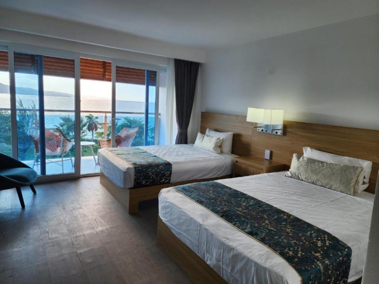 Habitación doble con dos camas y vista panorámica al mar desde balcón en Hotel 39 Jamaica
