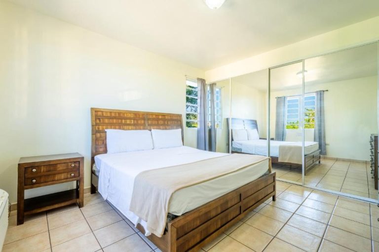 Habitación doble con cama matrimonial de madera y armario con espejo en West Coast Apartments