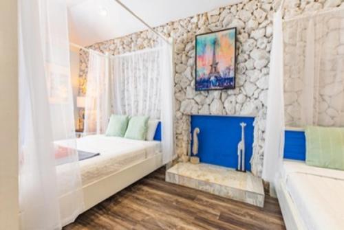 Habitación doble con dosel blanco y chimenea decorativa azul en Studio Palms BC