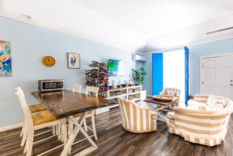 Sala de estar y comedor con mesas de madera y sillones a rayas en Studio Palms BC