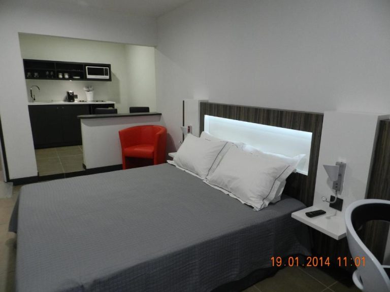 Habitación doble con cama king, kitchenette equipada y silla roja en Residence Fort Savane