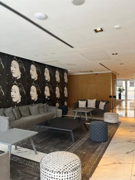 Lobby moderno con sofás y mural artístico de retratos en blanco y negro del Ilum Experience Home