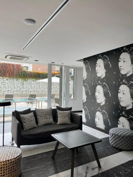 Zona lounge con sofá negro y mural artístico en blanco y negro del Ilum Experience Home