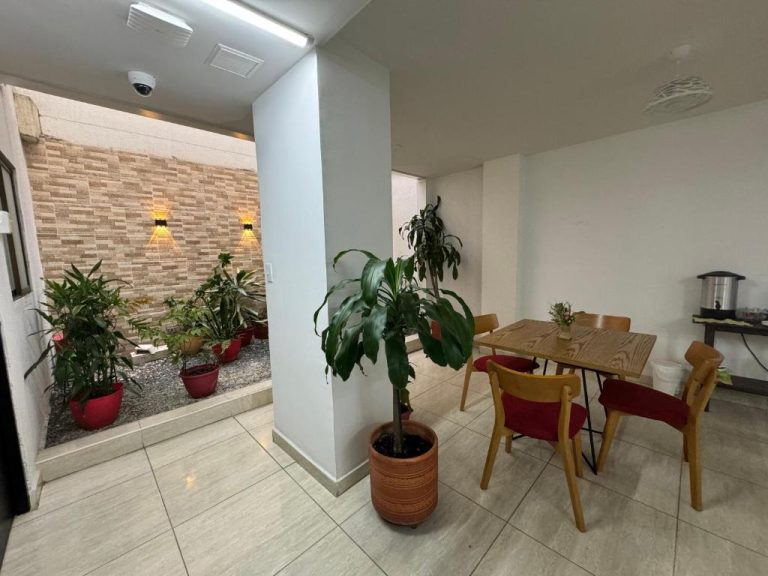 Área de desayuno con jardín interior y plantas del Hotel Mar Inn Cali, mesa de madera y sillas