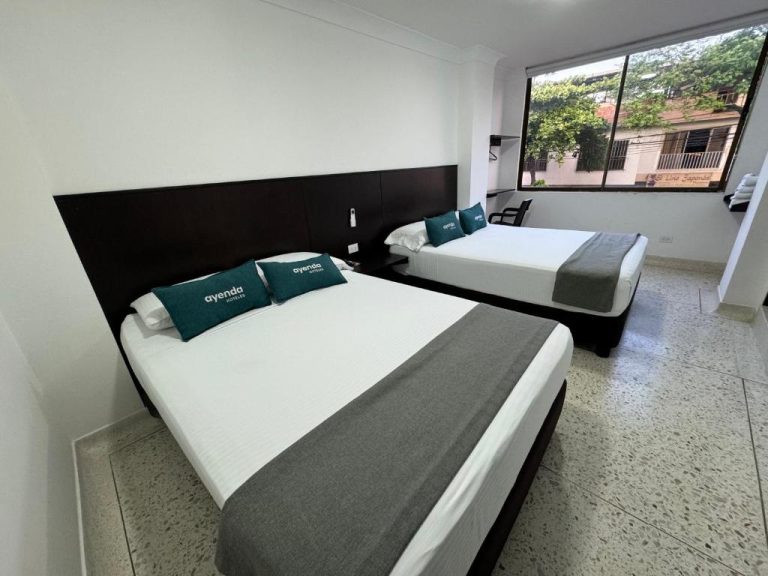 Habitación doble con dos camas y almohadas verdes en Hotel Mar Inn Cali, Colombia