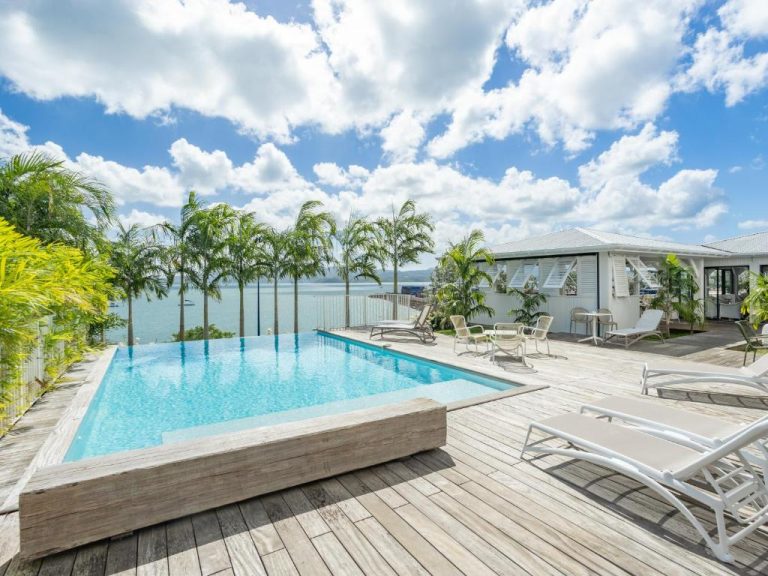 Piscina infinita con terraza de madera y vistas al mar del B&B Hotel Fort-de-France en Martinica