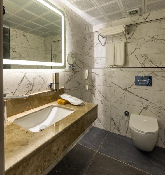 Baño de mármol con lavabo y espejo iluminado en el Belenli Resort Hotel