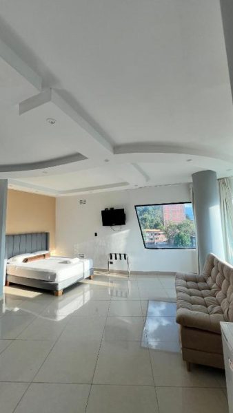 Suite amplia con cama doble, sofá y ventanal con vista exterior en Hotel Gran Conquistador 33