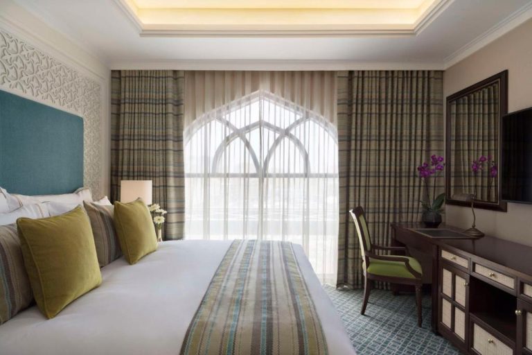 Habitación de lujo con ventanal de arco árabe y decoración elegante en Al Najada Doha Hotel by Tivoli
