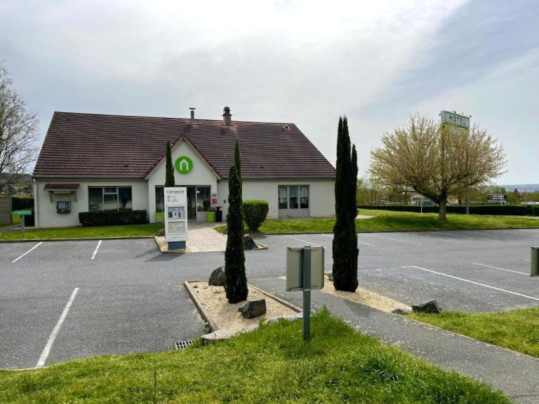 Fachada exterior y aparcamiento del Hotel Campanile Montluçon Saint-Victor con jardín y cipreses