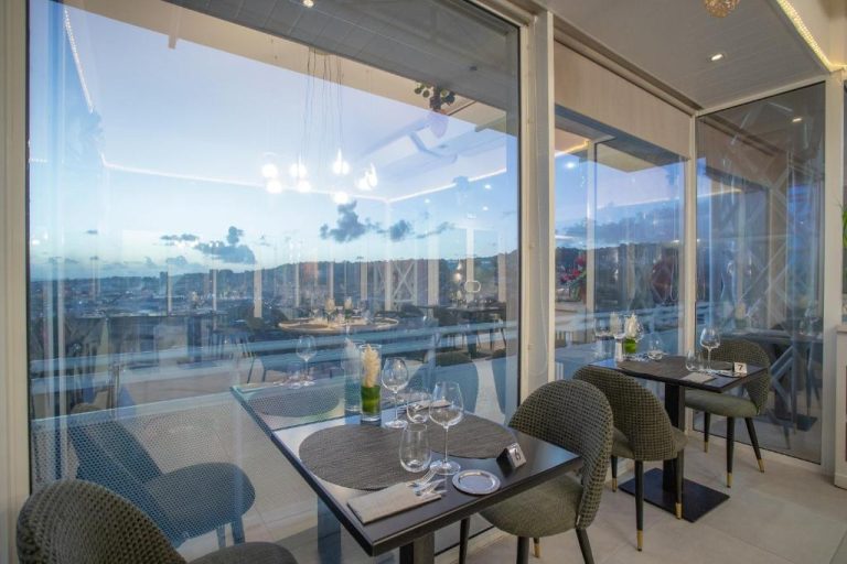 Restaurante con mesas elegantes y vistas panorámicas al atardecer en el Hotel Karibea La Valmenière