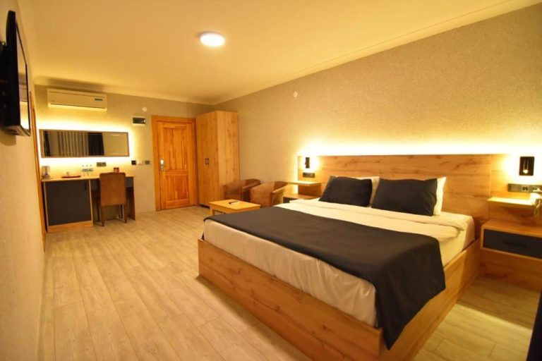 Habitación doble con cama king size y cabecero de madera iluminado en Green Palace Suite Hotel