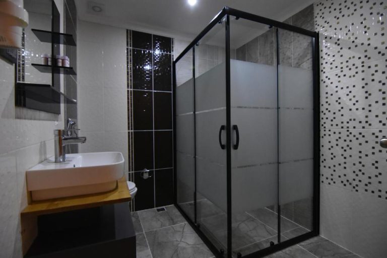 Baño moderno con cabina de ducha de cristal y lavabo en el Green Palace Suite Hotel