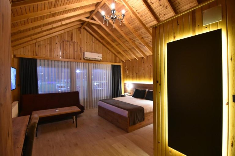 Habitación de cabaña de madera con cama doble y techo abuhardillado en Green Palace Suite Hotel
