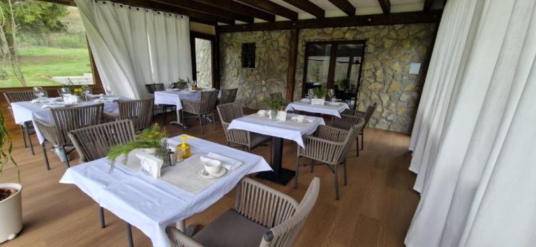 Restaurante interior con terraza acristalada y mesas con manteles blancos del Plitvice Inn