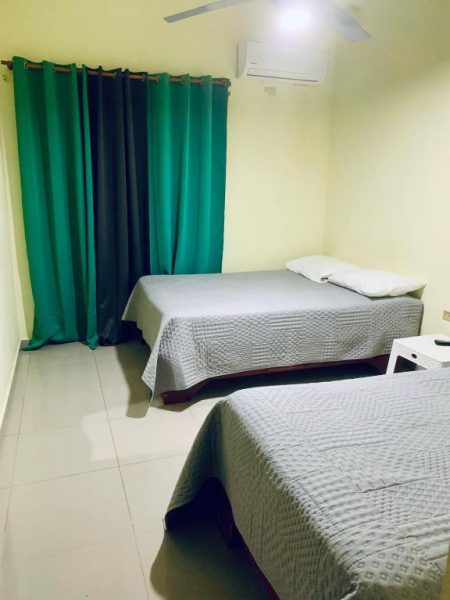Habitación twin con dos camas y cortinas verdes en Hotel Vista Sur con aire acondicionado