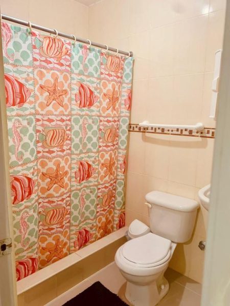 Baño completo con cortina de ducha temática marina en Hotel Vista Sur, con inodoro y bañera