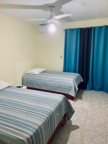 Habitación doble con dos camas y cortinas azules en Hotel Vista Sur con aire acondicionado