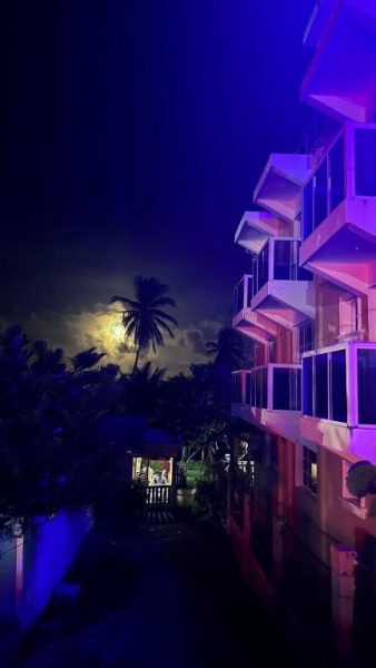 Vista nocturna del Hotel Vista Sur con terrazas iluminadas y luna llena entre palmeras tropicales