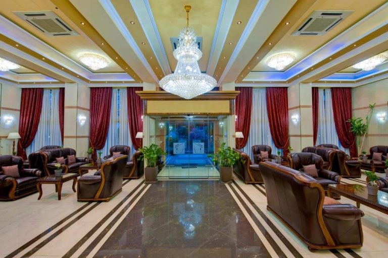 Lujoso lobby del Semeli Hotel con araña de cristal, sofás de cuero y suelo de mármol