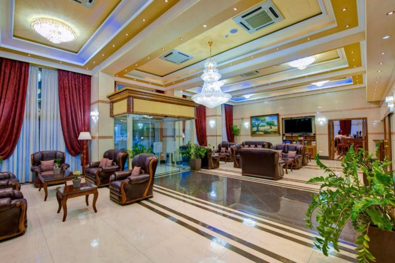 Elegante lobby del Semeli Hotel con sillones de cuero, araña de cristal y suelo de mármol