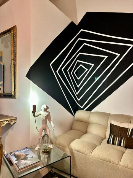 Salón con sofá beige y mural geométrico en blanco y negro en Thuishaven Boutique Mini-Resort