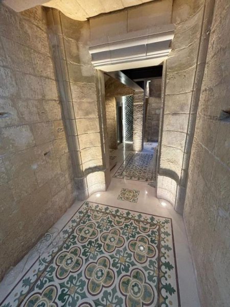 Corredor histórico de piedra con suelo de mosaico decorativo en Battery House