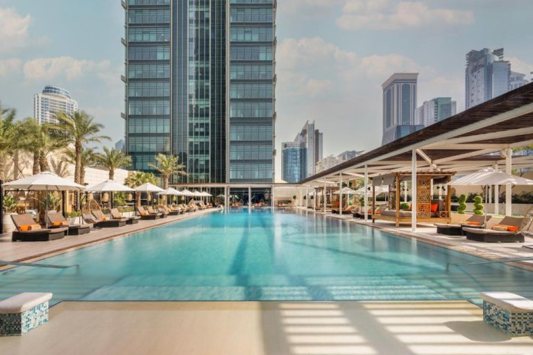 Piscina exterior del Marriott Marquis City Center Doha con tumbonas, sombrillas y vistas a los rascacielos