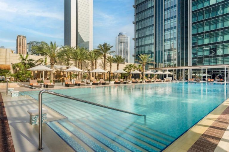 Piscina exterior con tumbonas y palmeras del Marriott Marquis City Center Doha con rascacielos al fondo
